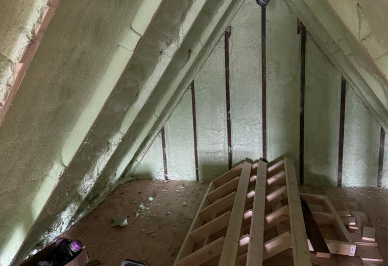 Green spray foam applied between the rafters of a narrow attic