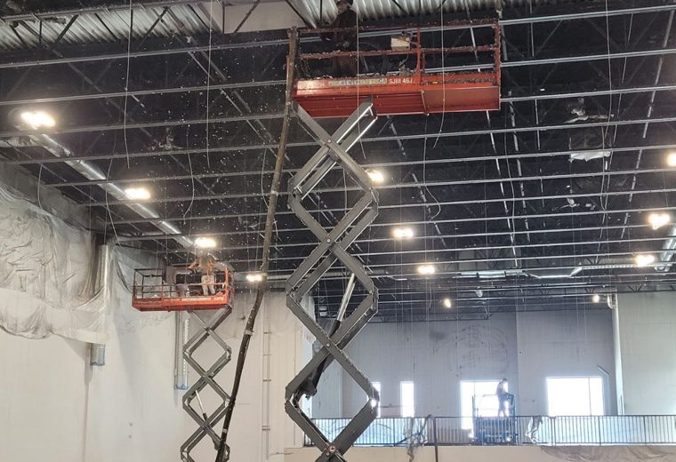 Crew working from scissor lifts beneath an open commercial ceiling